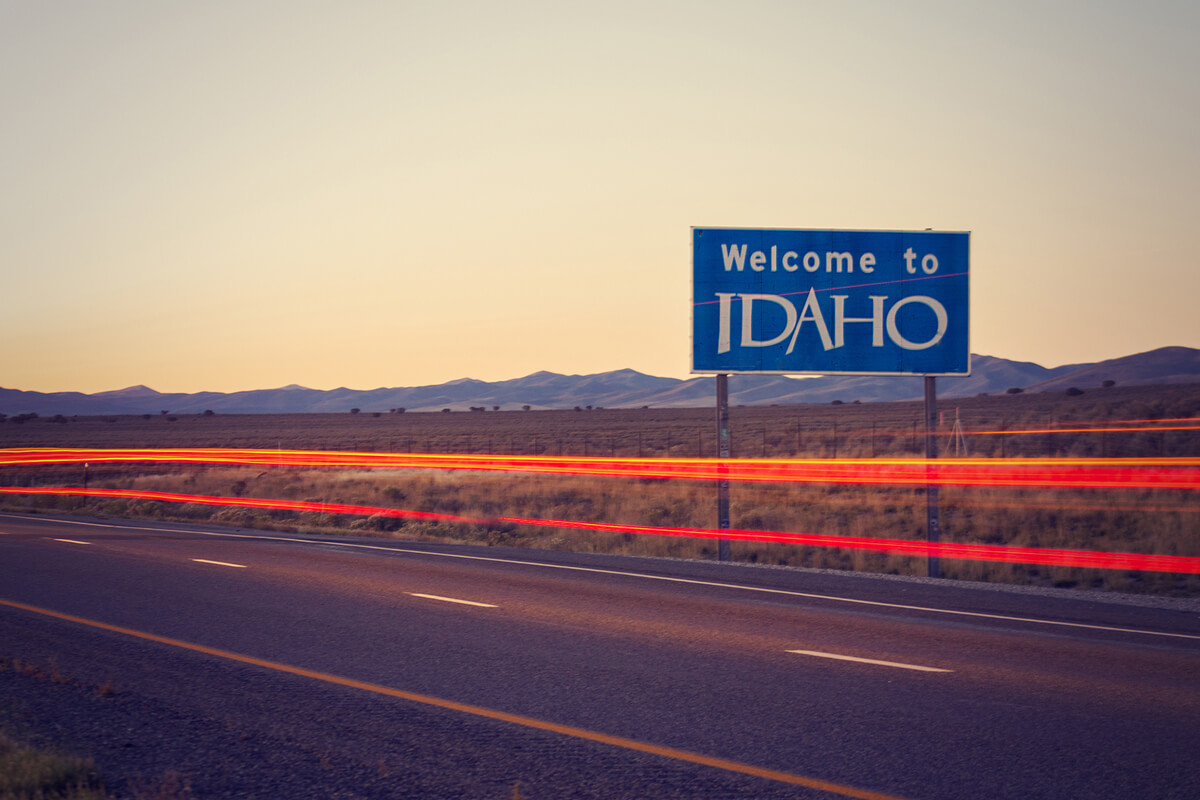 welcome to Idaho sign alongside a road at sunset