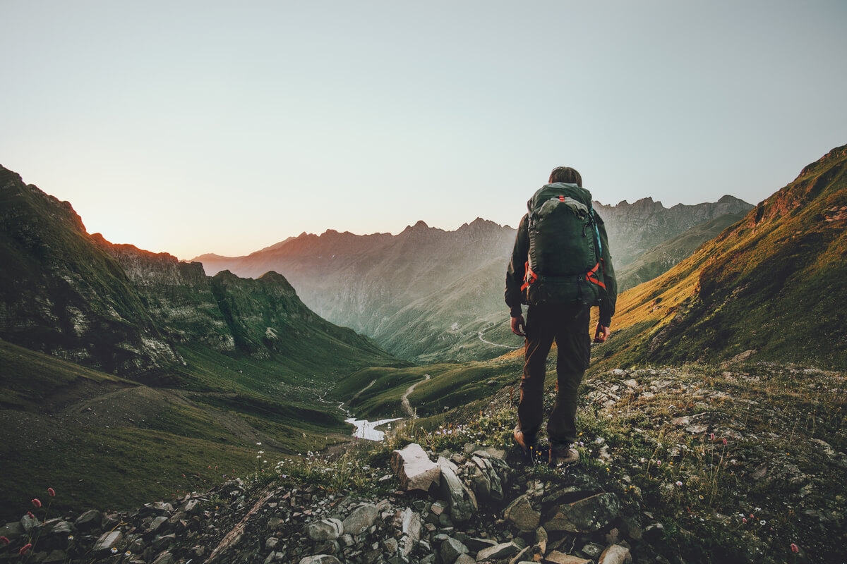 Man hiking at sunset in the Idaho mountains with a heavy backpack, outdoor adventure, travel safely