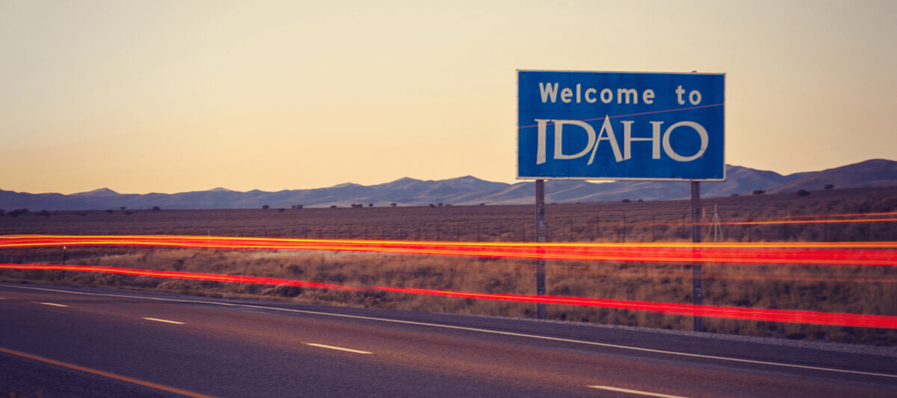 Welcome to Idaho state sign on highway at sunset