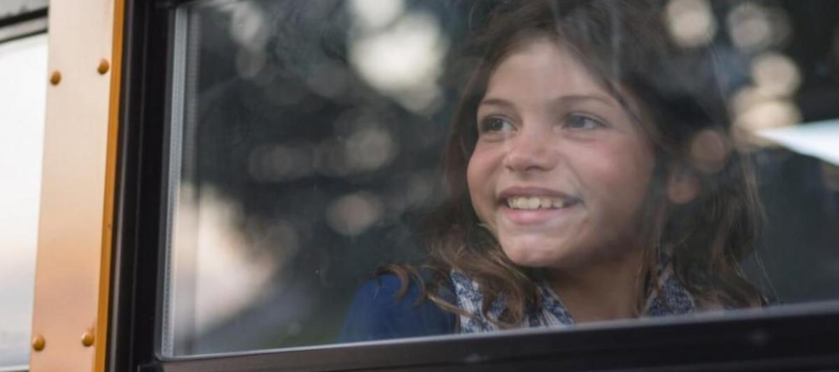 Young female student looking out the window of a school bus